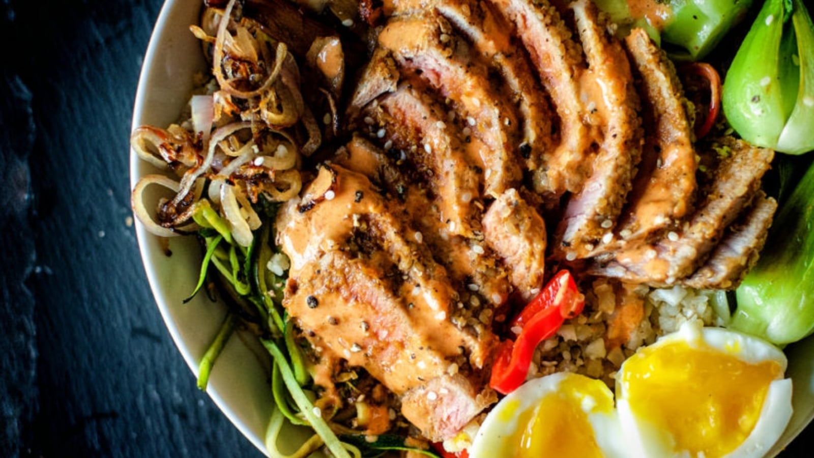 Tuna bowl with sesame crusted tuna slices over rice and vegetables.
