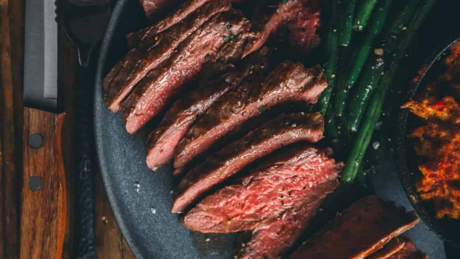 Pan-seared blade steak with a dark crust sliced to reveal juicy pink center on the cutting board.