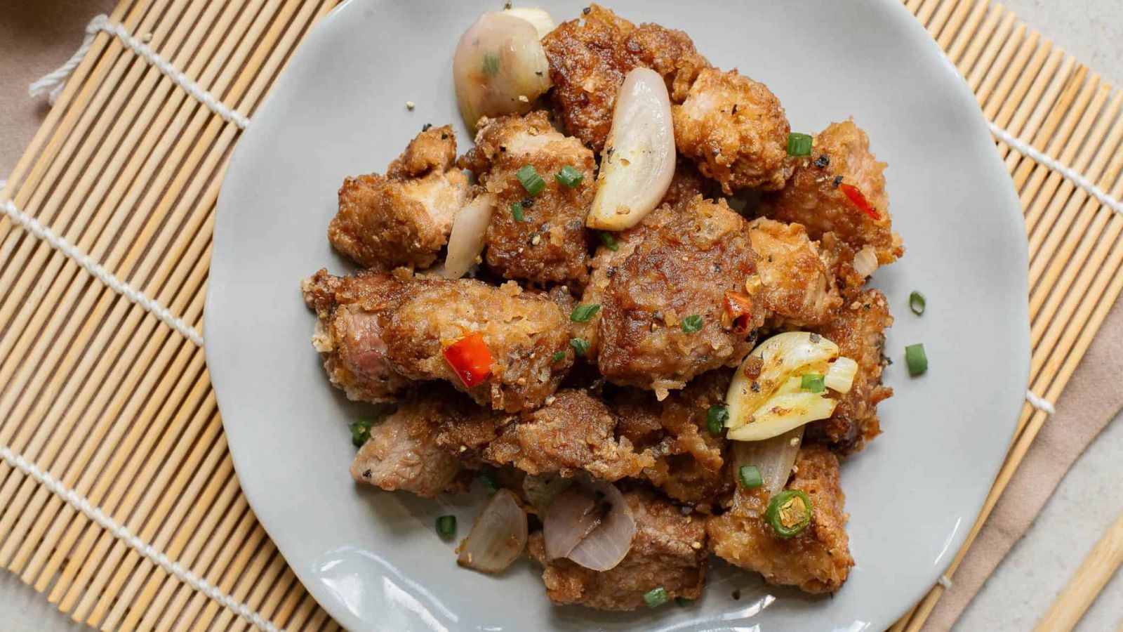 A plate of Salt Pepper Pork Chop Bites on a bamboo mat.