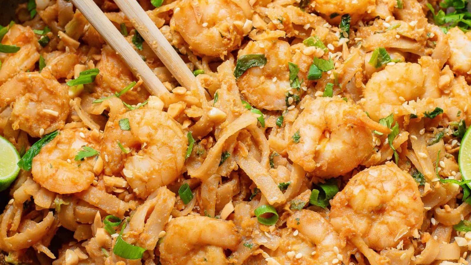 A pan full of shrimp and noodles with chopsticks.