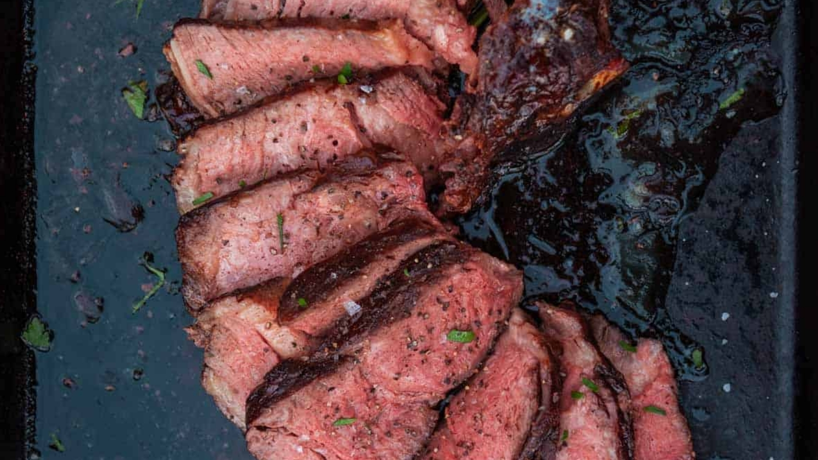 Smoked cowboy steak with dark bark and a red juicy center sliced thick.