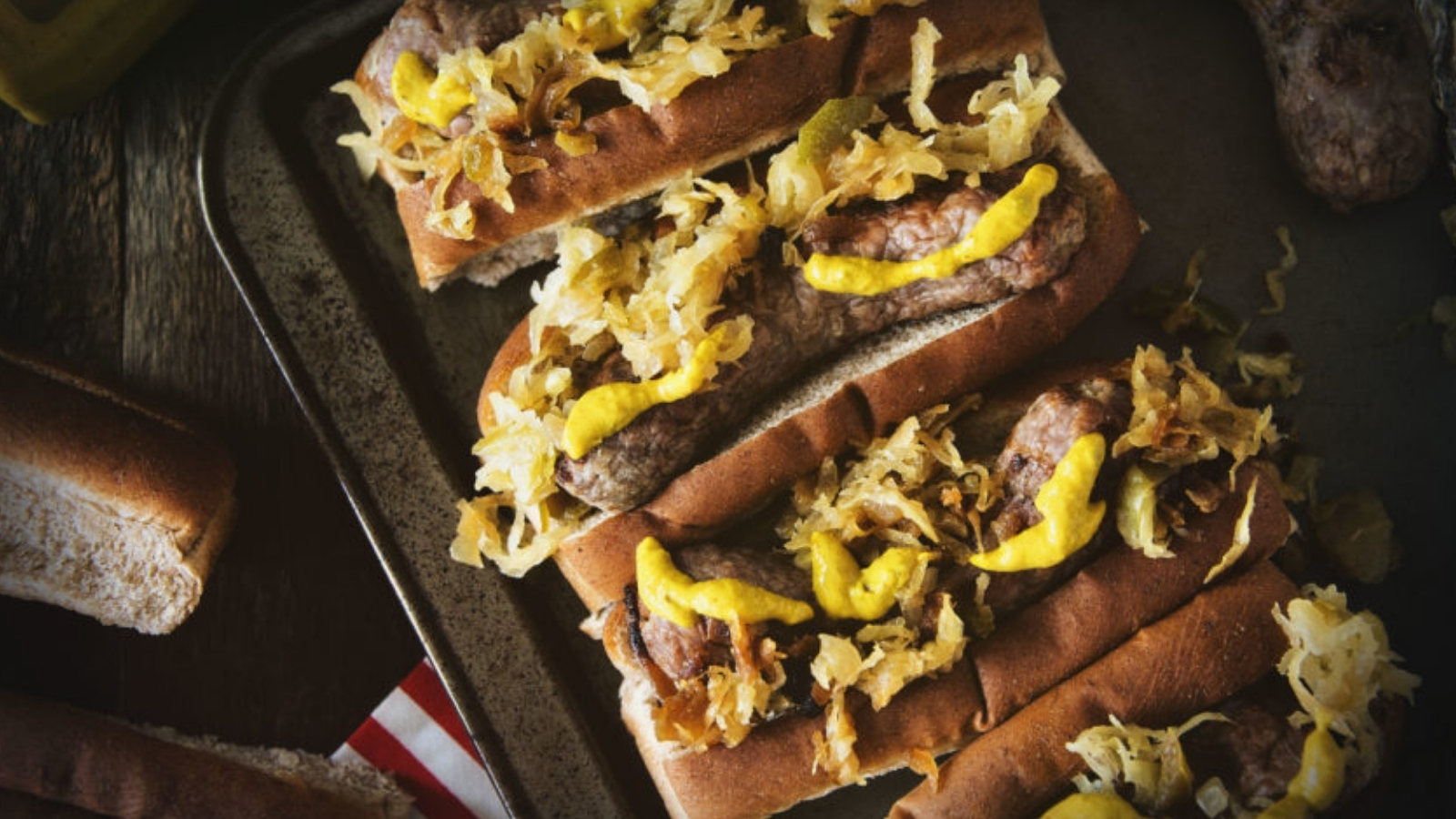 Brats grilled with spicy mustard and sauerkraut piled on top.