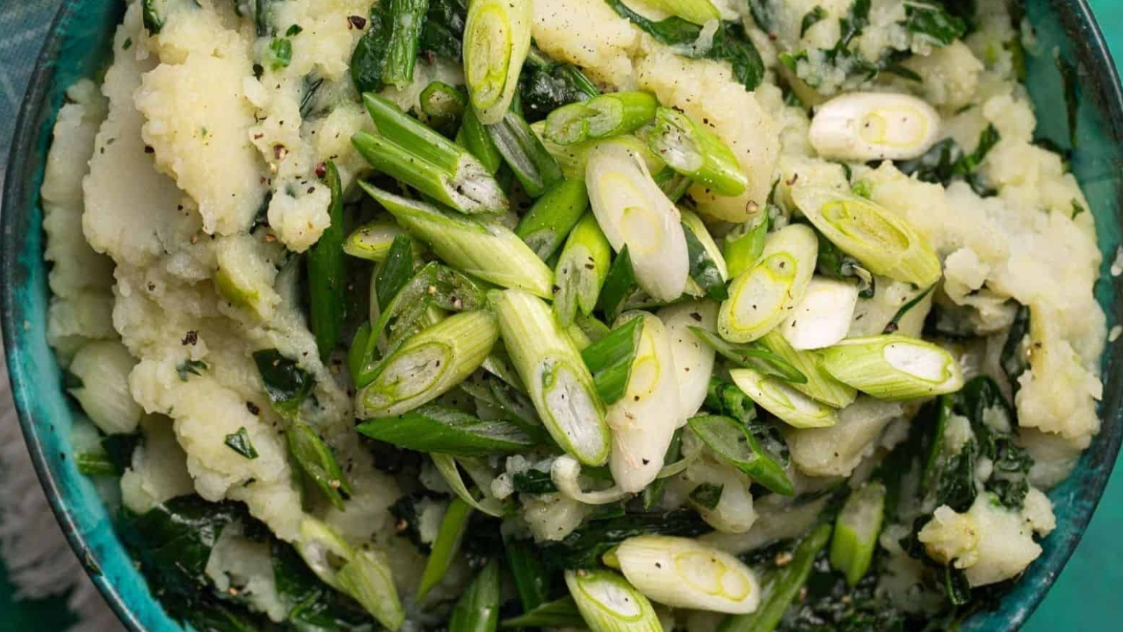 A bowl of colcannon, a traditional Irish dish and a good choice for sides, features mashed potatoes mixed with green leafy vegetables and topped with chopped scallions.