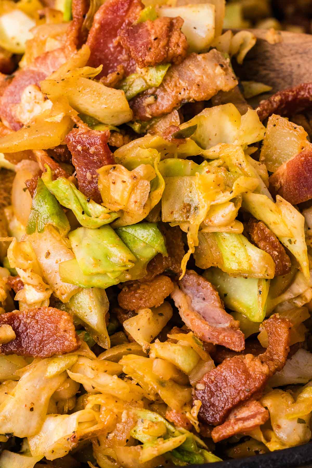 A close-up of fried cabbage mixed with crispy bacon pieces and seasonings.