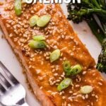 Close-up of a cooked miso glazed salmon fillet garnished with sesame seeds and sliced green onions, served with a side of broccolini. Text overlay reads, "How To Make Miso Glazed Salmon.