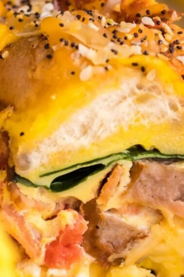 Close-up of a breakfast casserole featuring layers of bread, sausage, cheese, eggs, spinach, and seasonings.