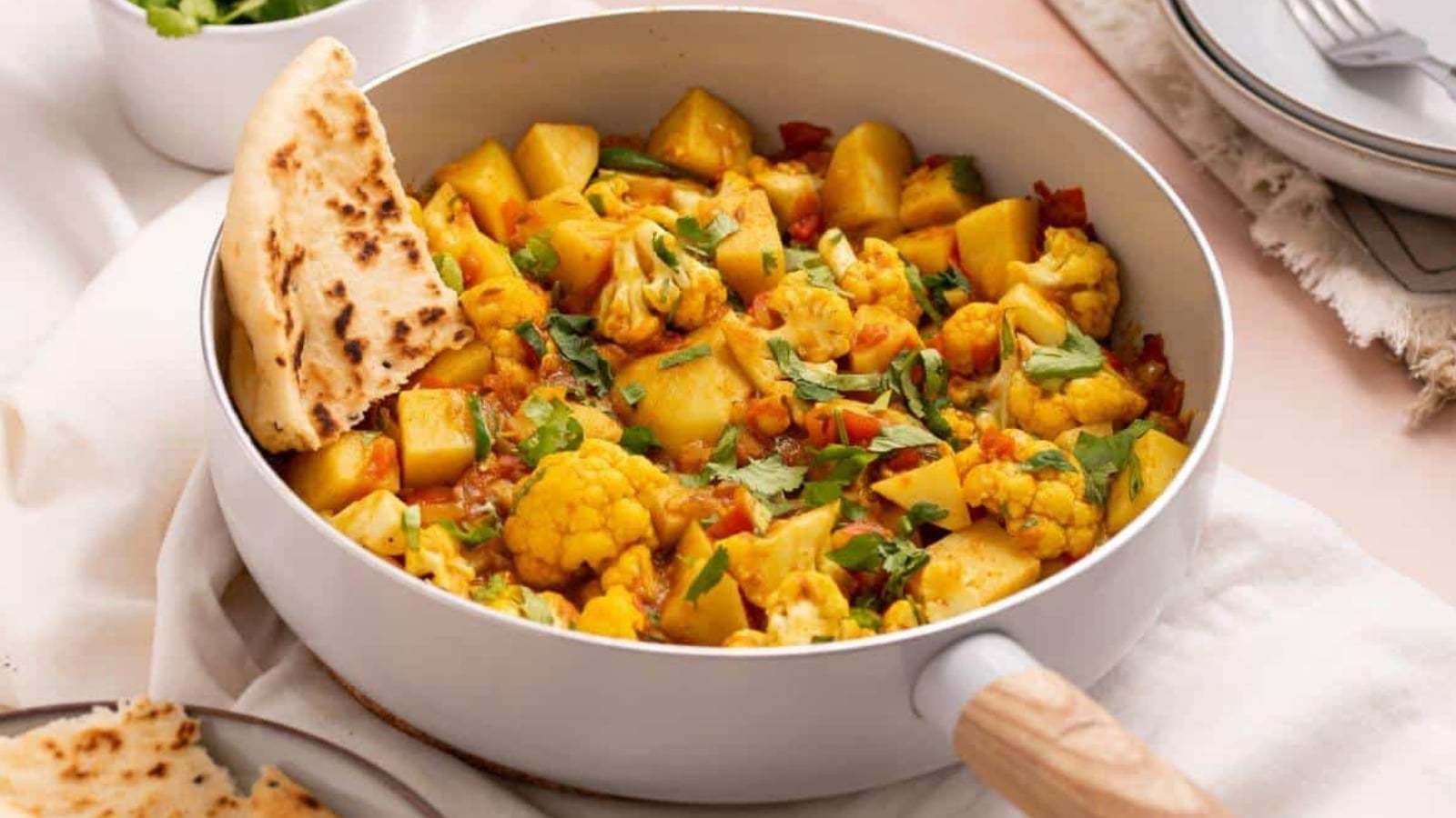 Aloo gobi masala in skillet with naan bread.