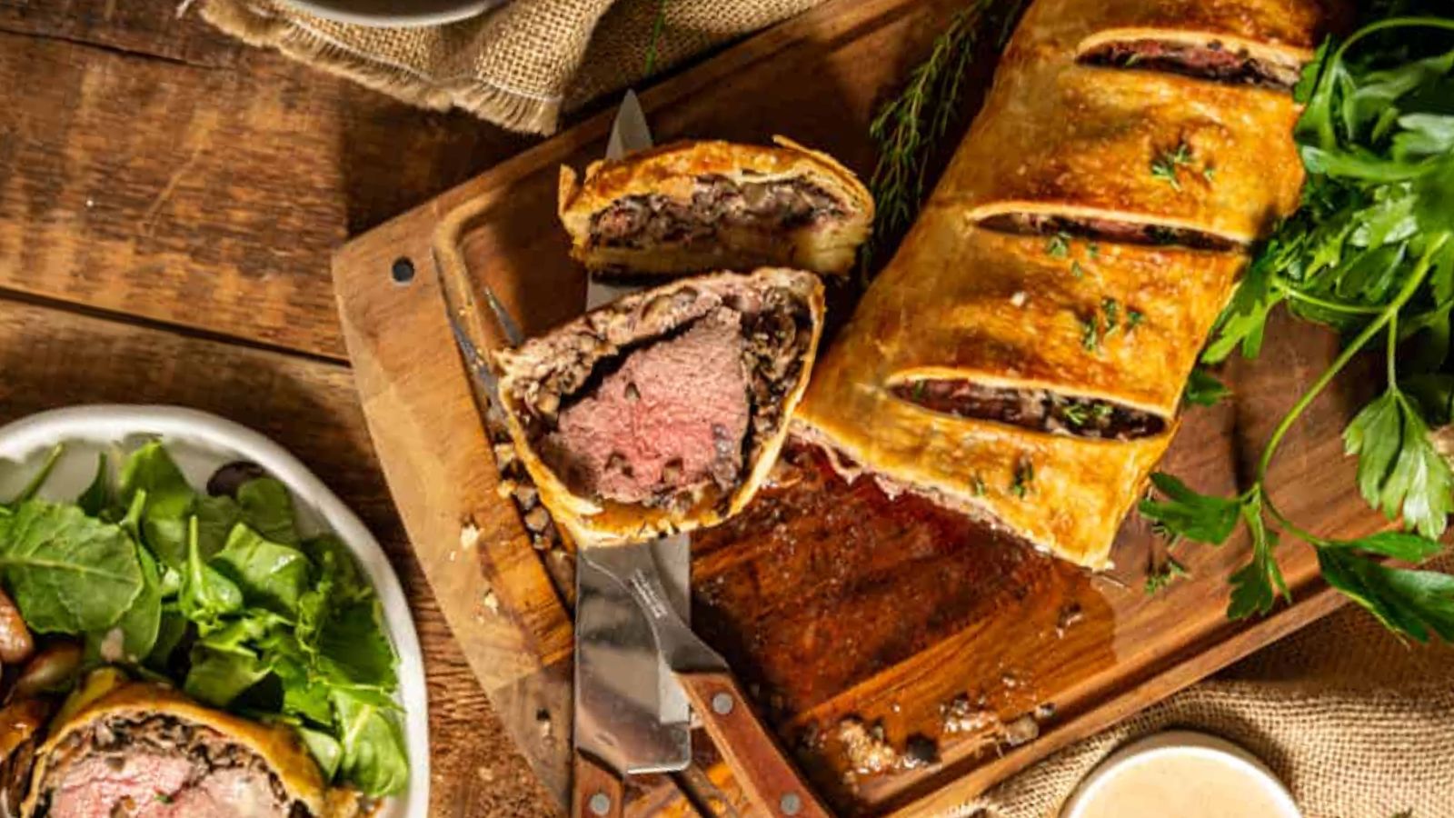 Wellington sliced to reveal rare beef center wrapped in pastry and mushroom mixture.