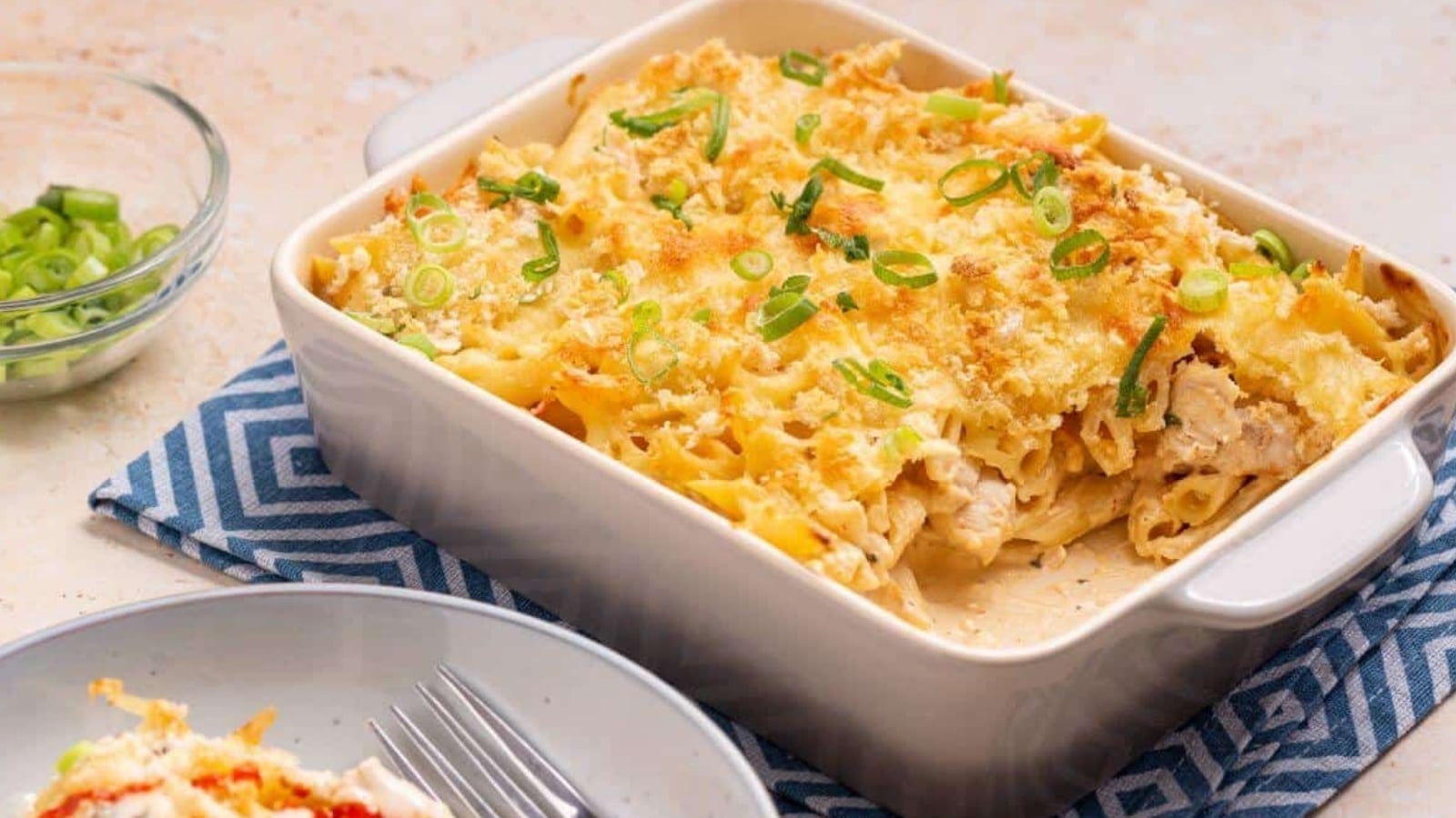 Serving of buffalo chicken pasta bake with casserole dish.