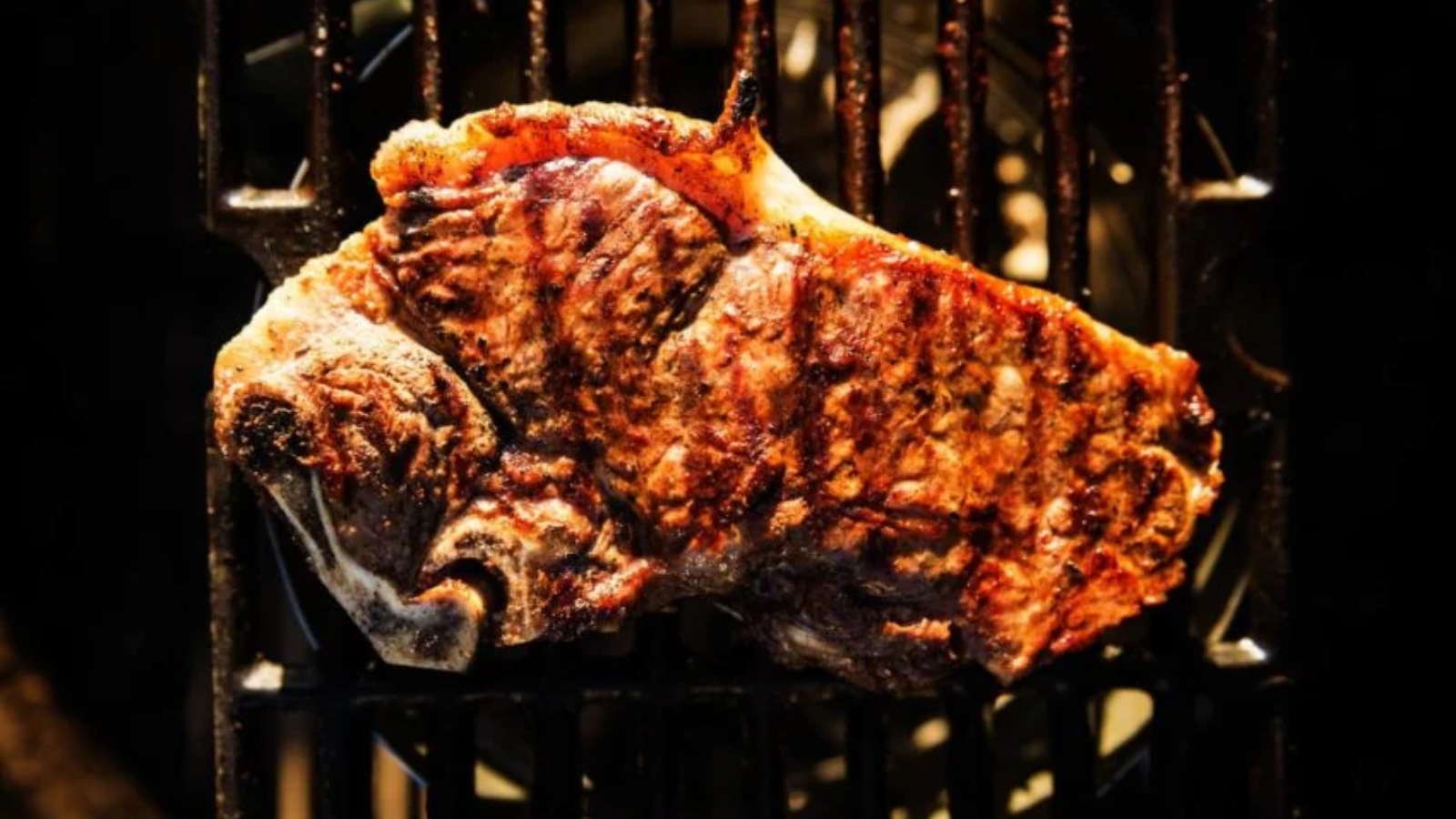 Steaks seared over chimney starter flames creating high-heat char.