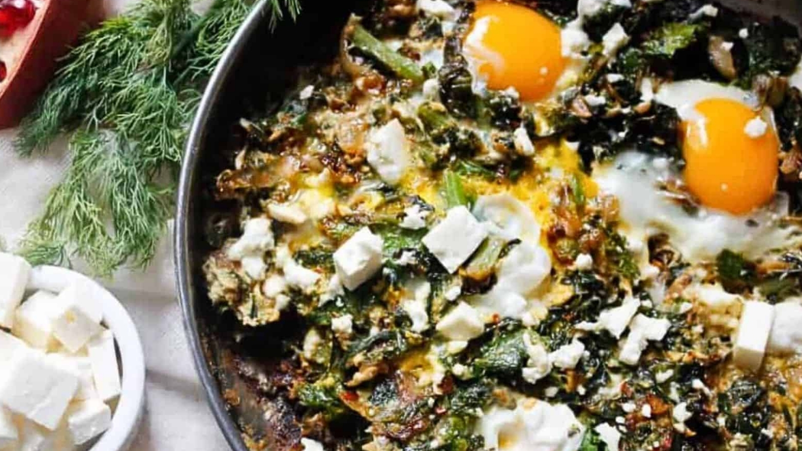 A skillet with eggs, spinach and pomegranate.