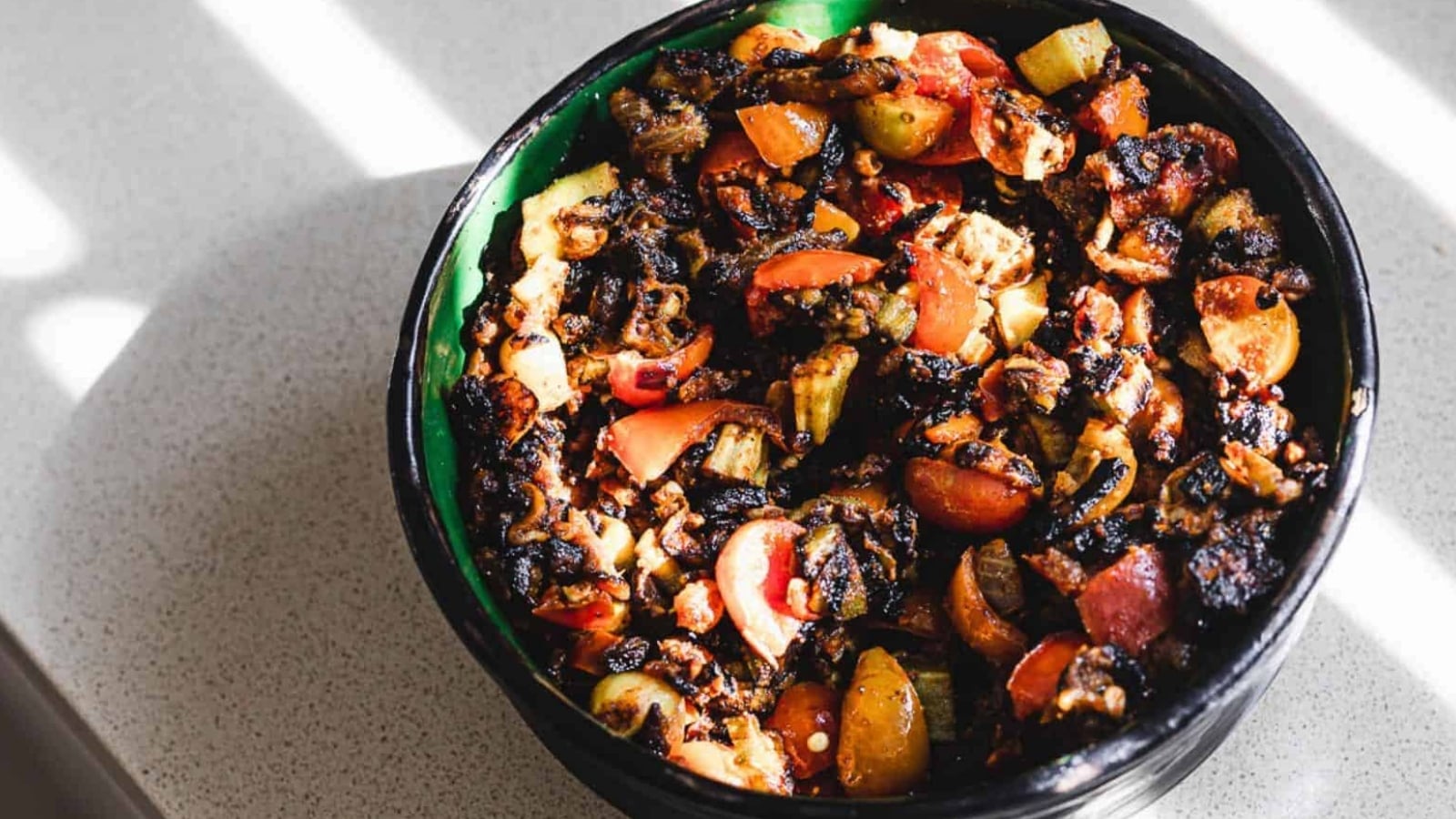 A black bowl filled with vegetables on a table.