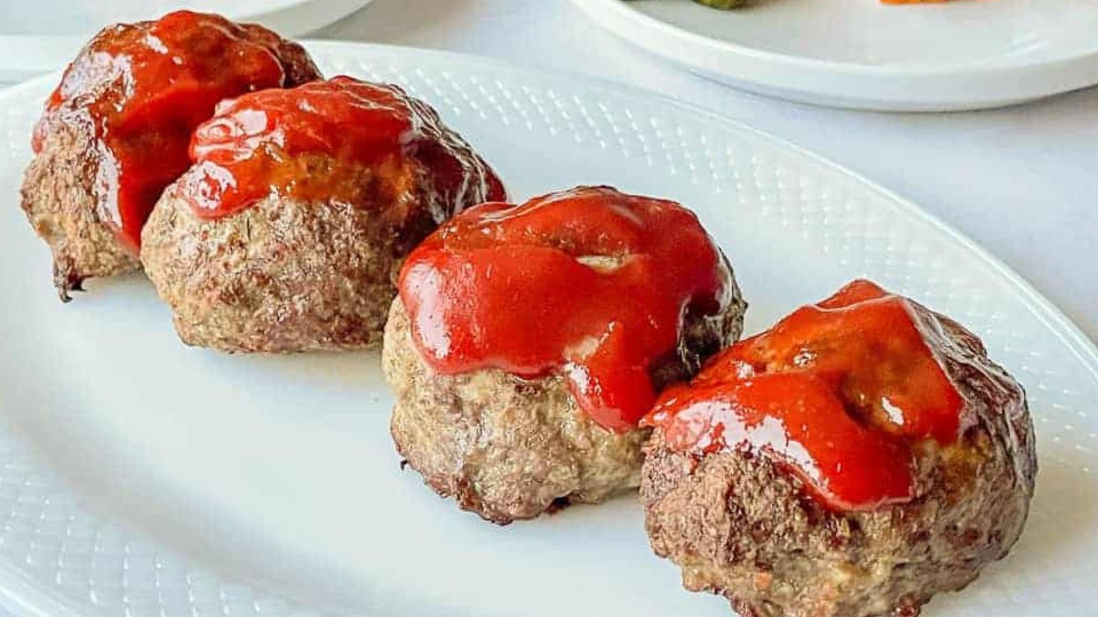 Mini Meatloaves line up on a platter with a glaze on top.