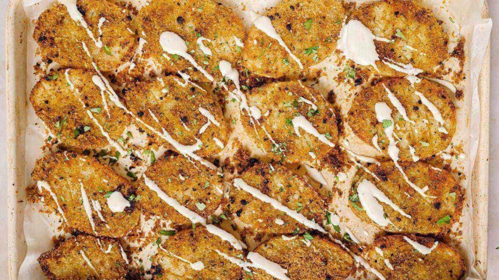 A baking sheet with garnished parmesan crusted potatoes on it.