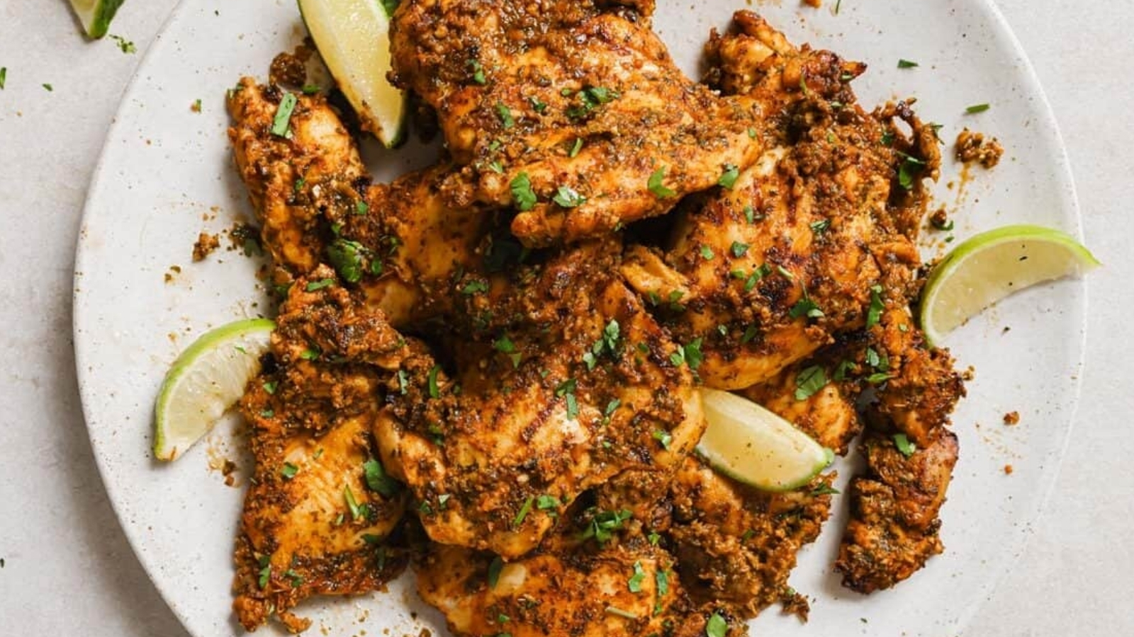 Pollo asado on a white plate with lime wedges.