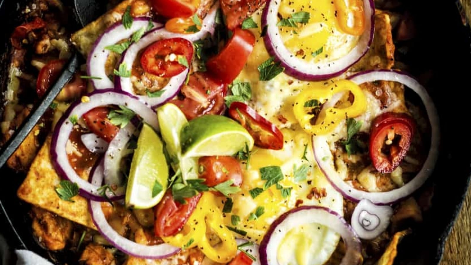 Chilaquiles topped with smoked chicken pieces layered over crisp tortillas and green sauce.