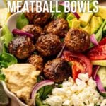 A bowl with lamb meatballs, avocado, tomato slices, red onion, feta cheese, salad greens, and hummus with text promoting a spicy lamb meatball bowl recipe.