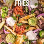 A close-up of San Diego style carne asada fries topped with steak, guacamole, salsa, jalapeños, onions, cheese, and lime wedges. Text overlays provide a recipe link.