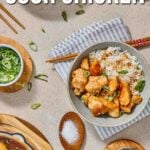 Top-down view of sweet and sour chicken with rice, garnished with green onions, chopsticks, a bowl of sauce, and a spoonful of sugar on a beige surface.