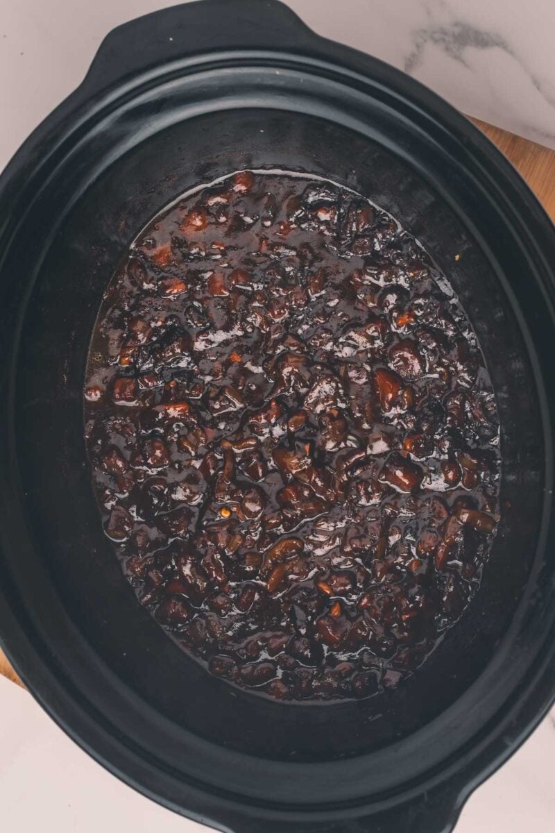 Slow cooker filled with a dark, chunky bacon jam.