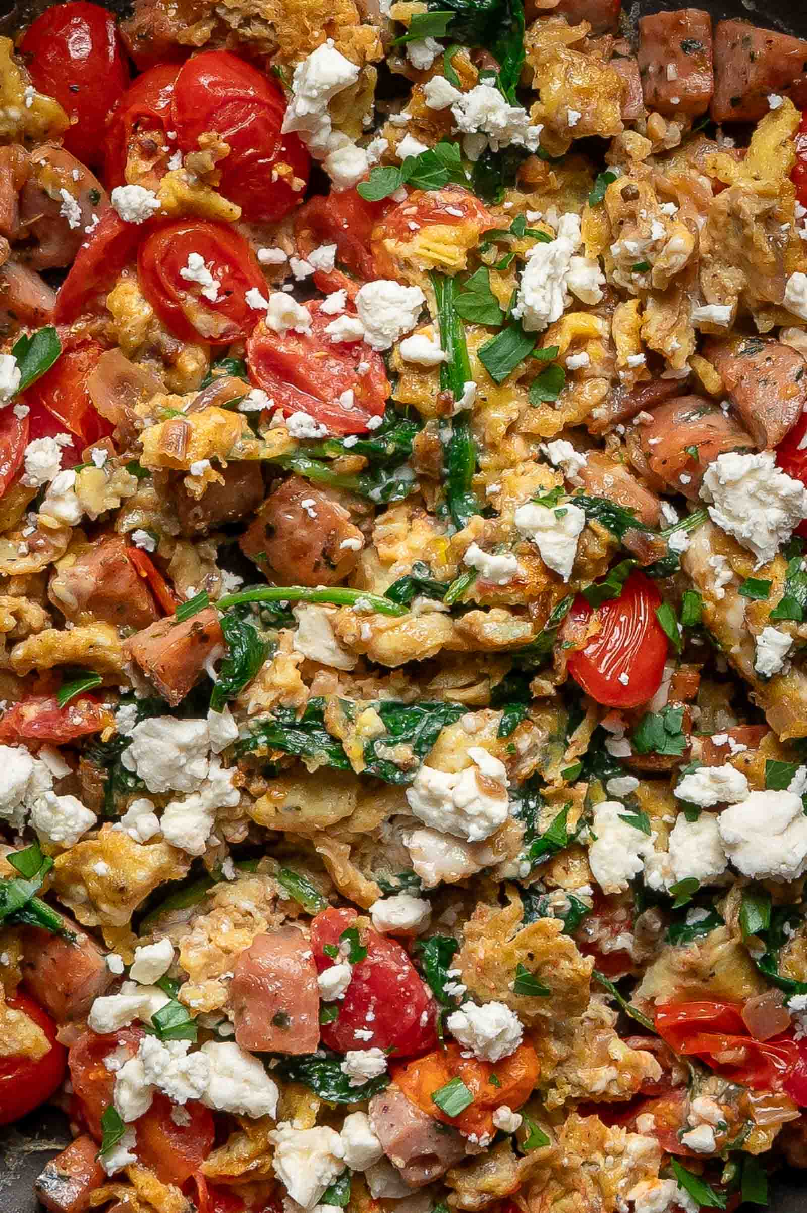 Greek scrambled eggs mixed with diced ham, cherry tomatoes, wilted greens, and topped with crumbled feta cheese.
