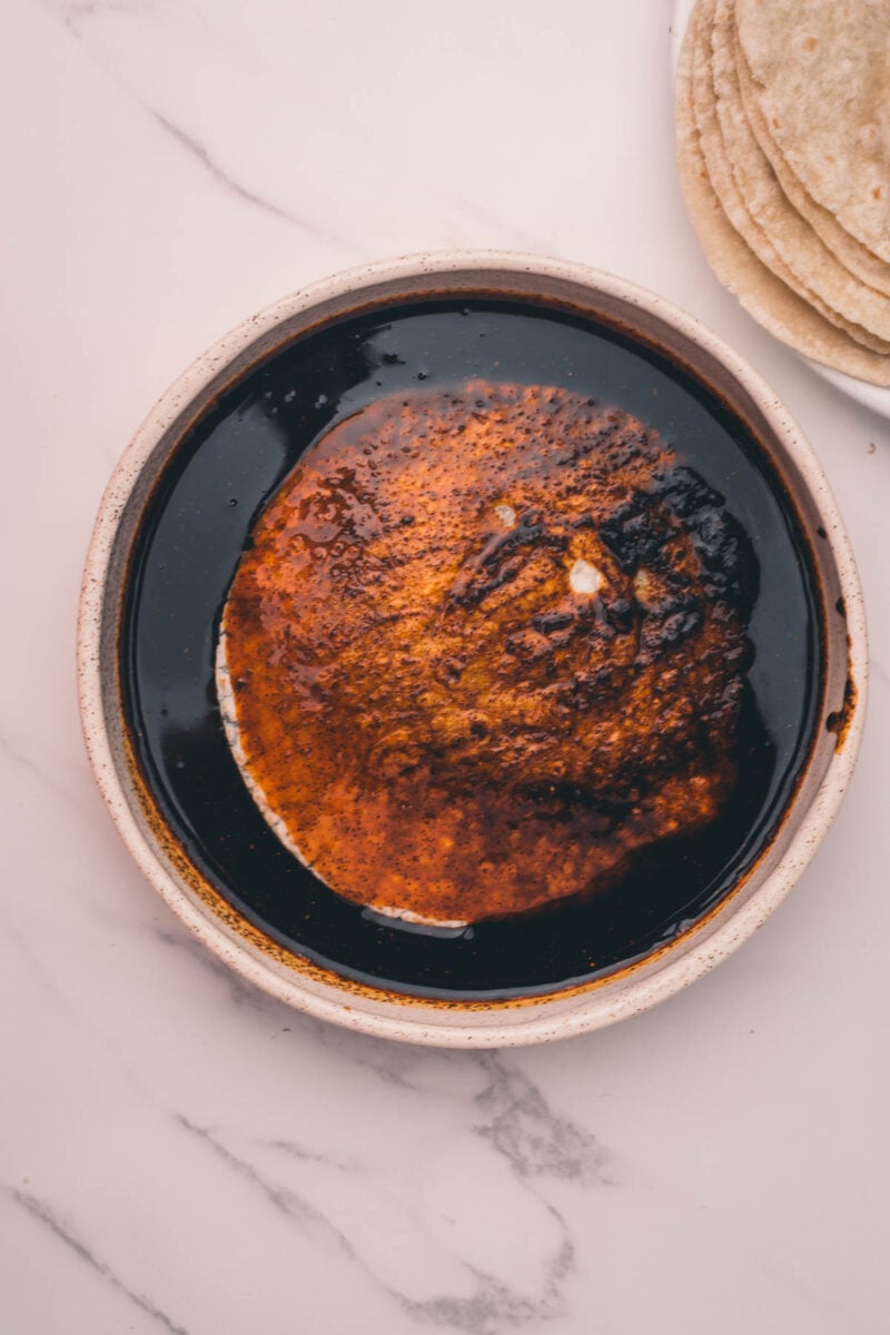 Tortilla being dipped in beef consomé.