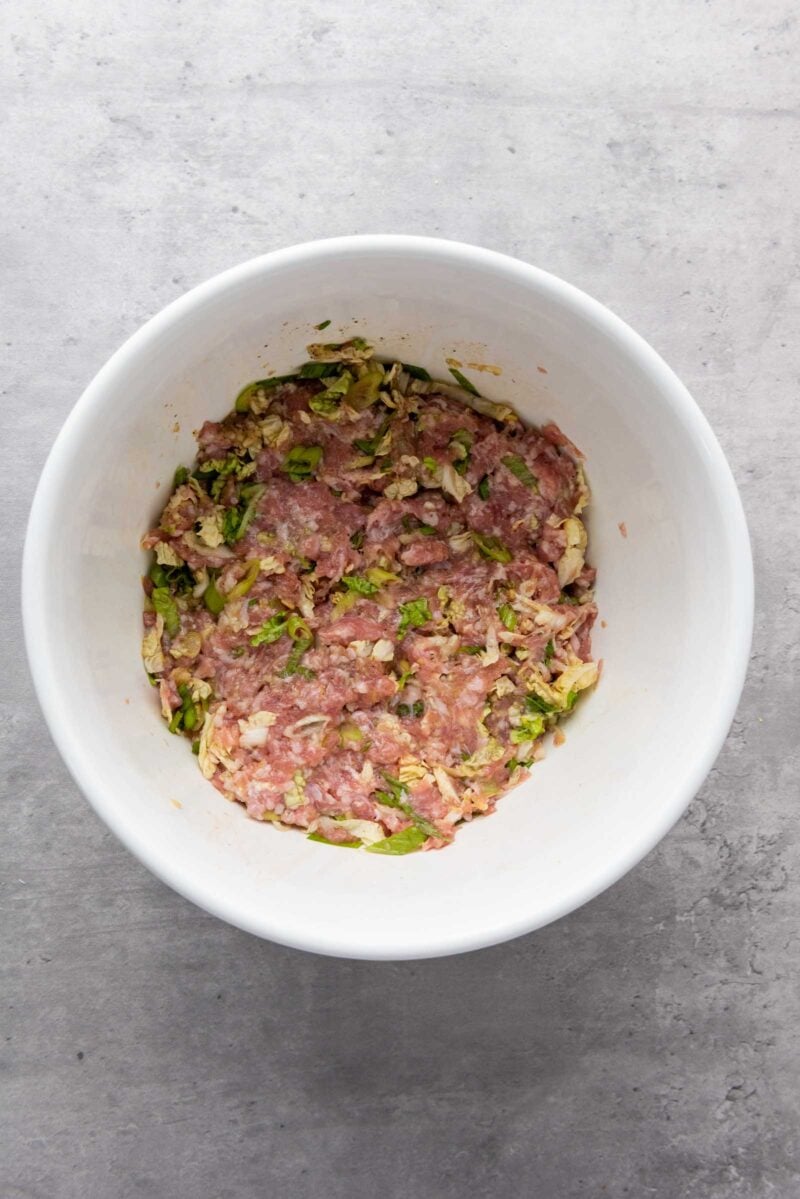 A white bowl containing a ground pork dumpling filling.