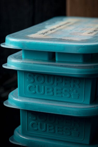 Stack of blue Souper Cubes containers with lids, used for freezing and storing food; label is visible on the top container.