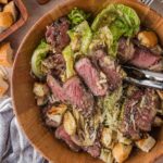 The full bowl of grilled steak Caesar salad with tongs, the grilled romaine spooned with dressing rather than tossed.