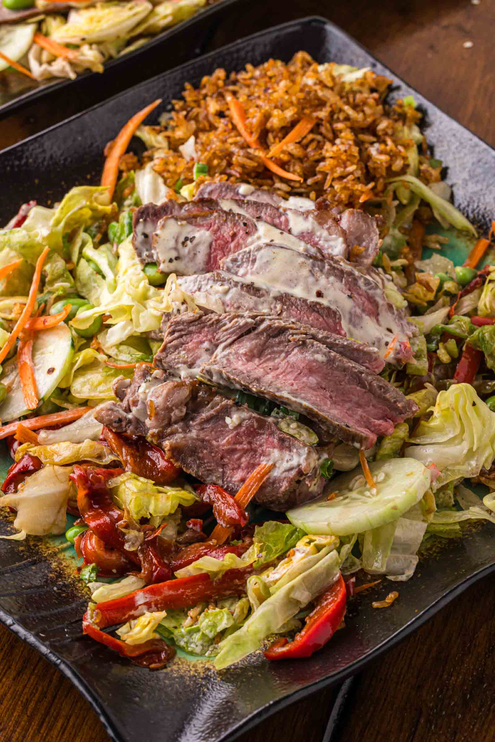 Sliced steak with creamy yum yum sauce served over ginger dressing tossed salad and crispy rice.