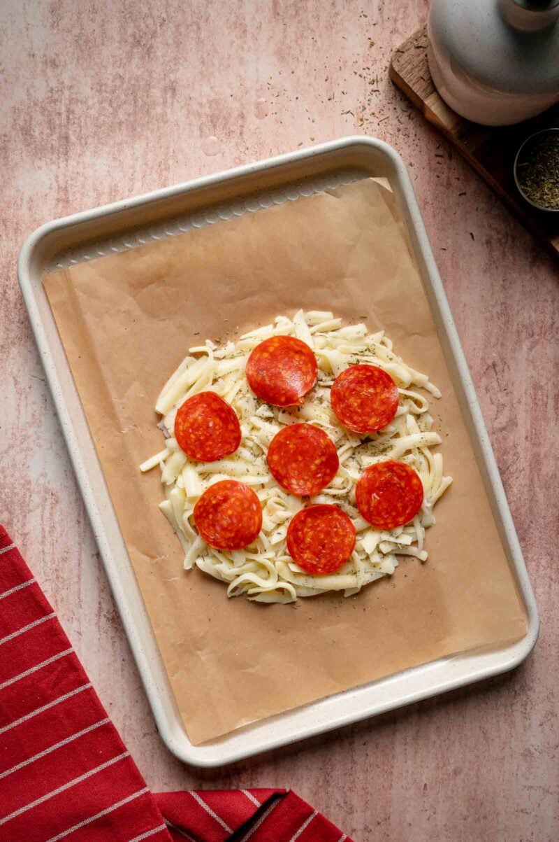 Unbaked pepperoni pizza wrap on parchment-lined baking sheet, viewed from above.