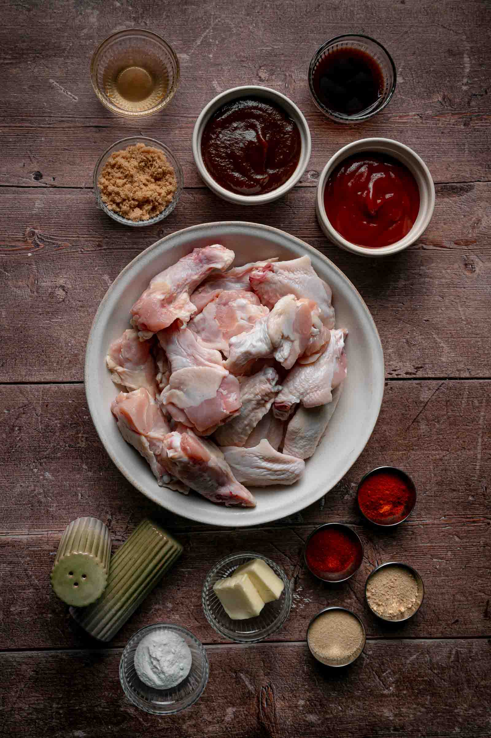 Ingredients for apple butter BBQ wings: raw wings, apple butter, ketchup, brown sugar, cider vinegar, Worcestershire, paprika, baking powder and butter.