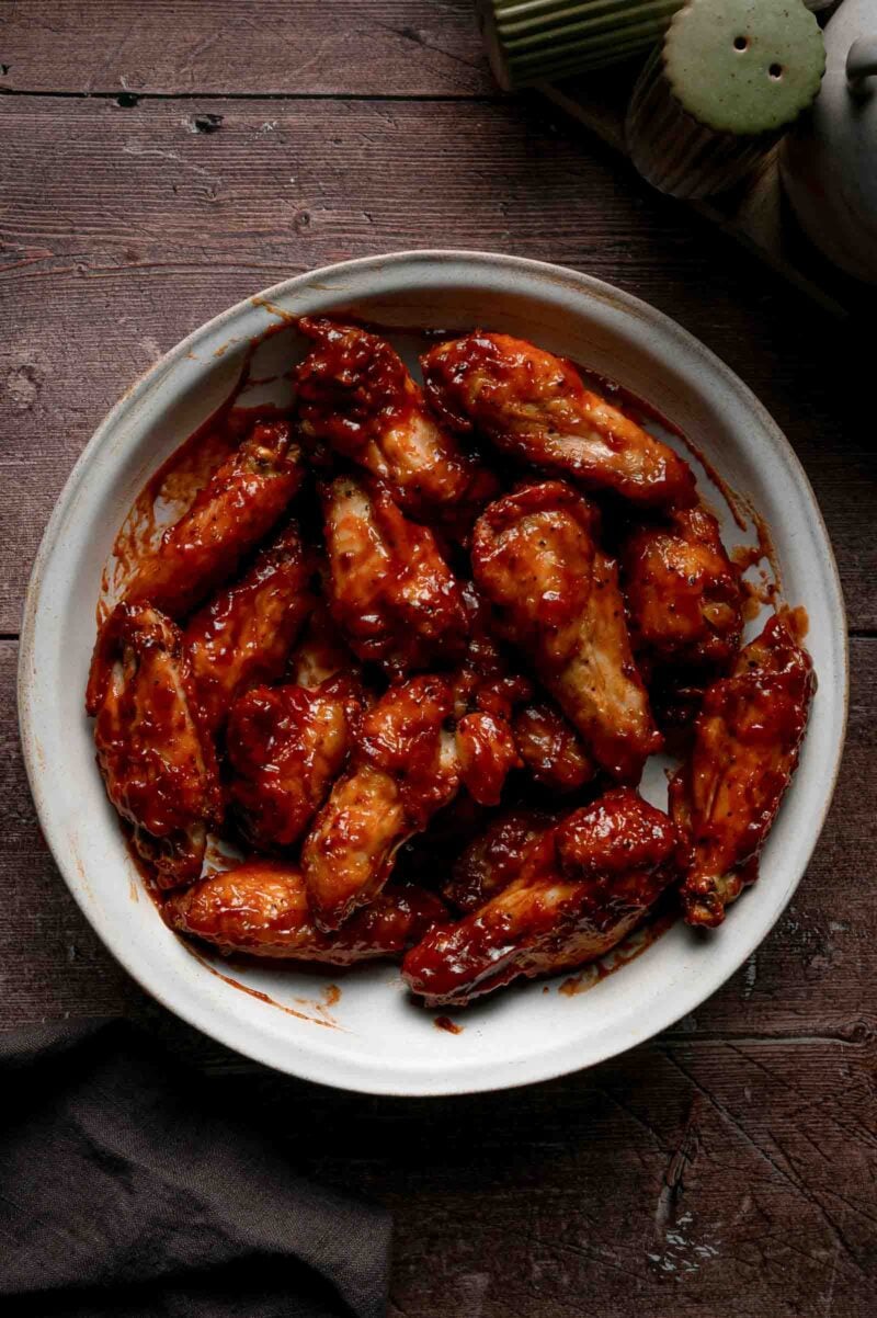 Baked chicken wings tossed in the bowl until every piece is lacquered in glossy apple butter BBQ sauce.