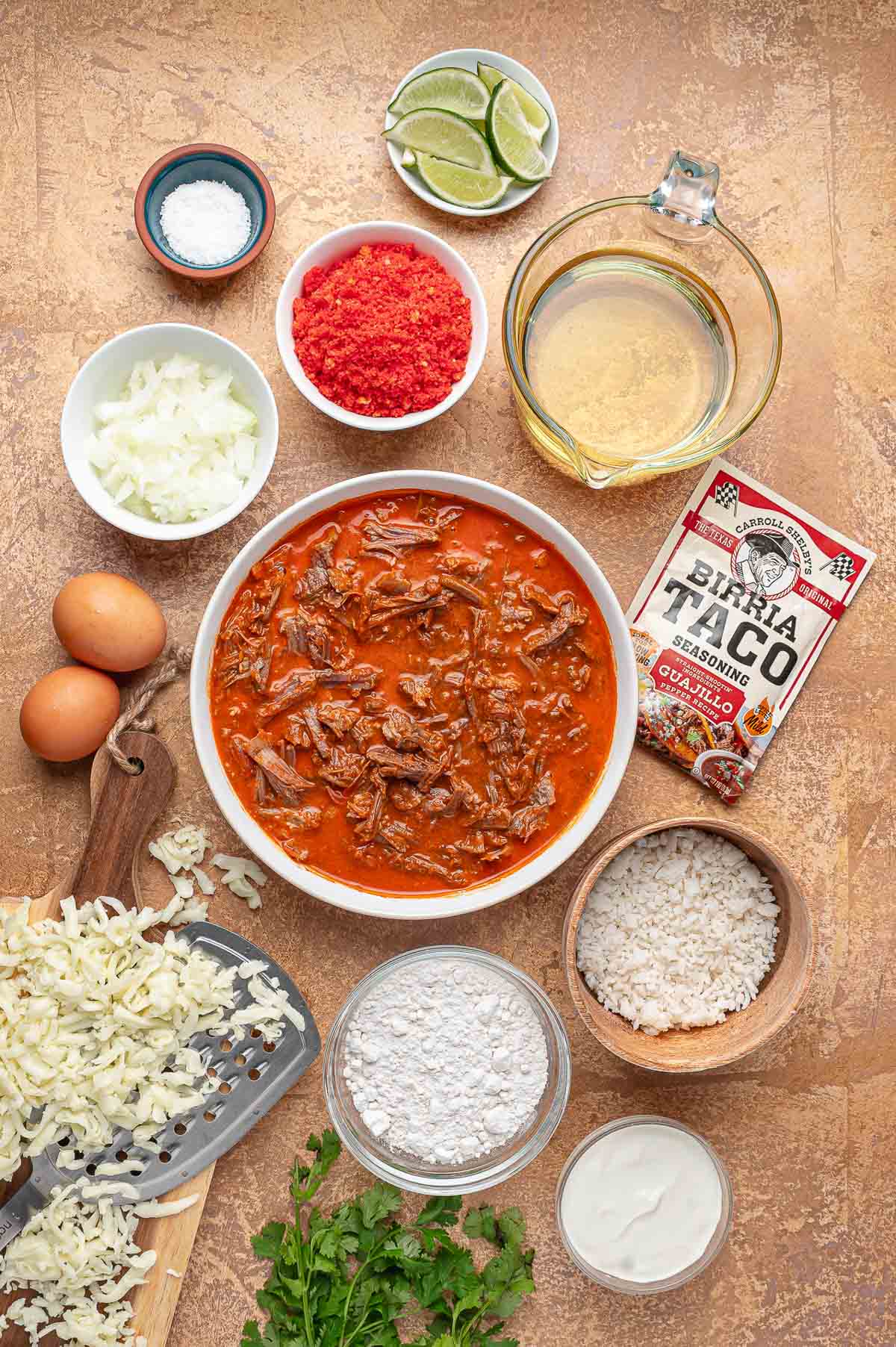 Ingredients for birria balls: leftover beef birria in consomé, Oaxaca cheese, rice, crushed Hot Cheetos, flour, eggs, onion, lime and birria taco seasoning.