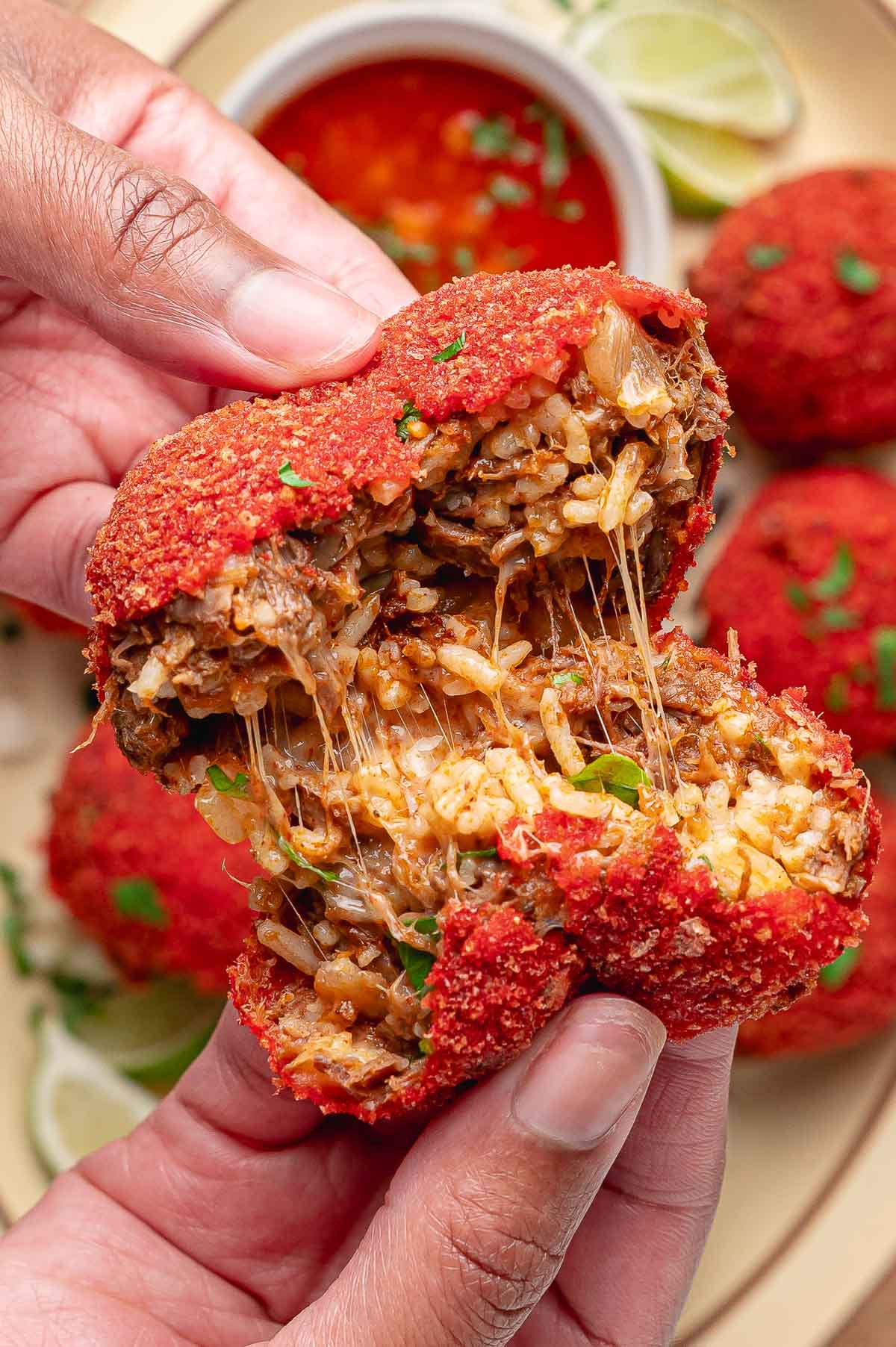 A Hot Cheeto birria ball pulled apart by hand, cheese stretching between the halves over the beef and rice filling.