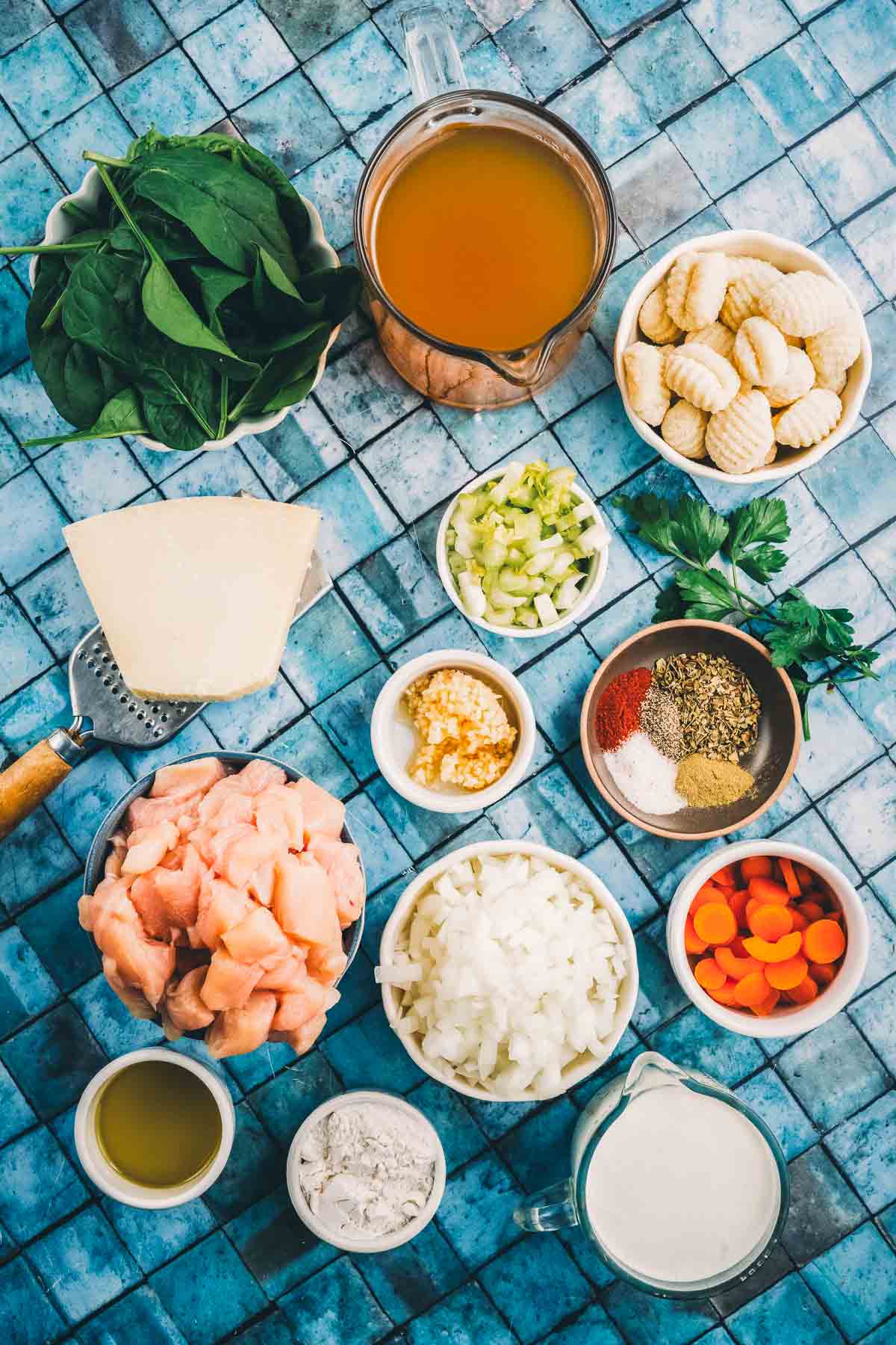 Ingredients for Italian chicken gnocchi soup: diced raw chicken, potato gnocchi, spinach, onion, carrot, celery, garlic, parmesan, flour, cream and broth.