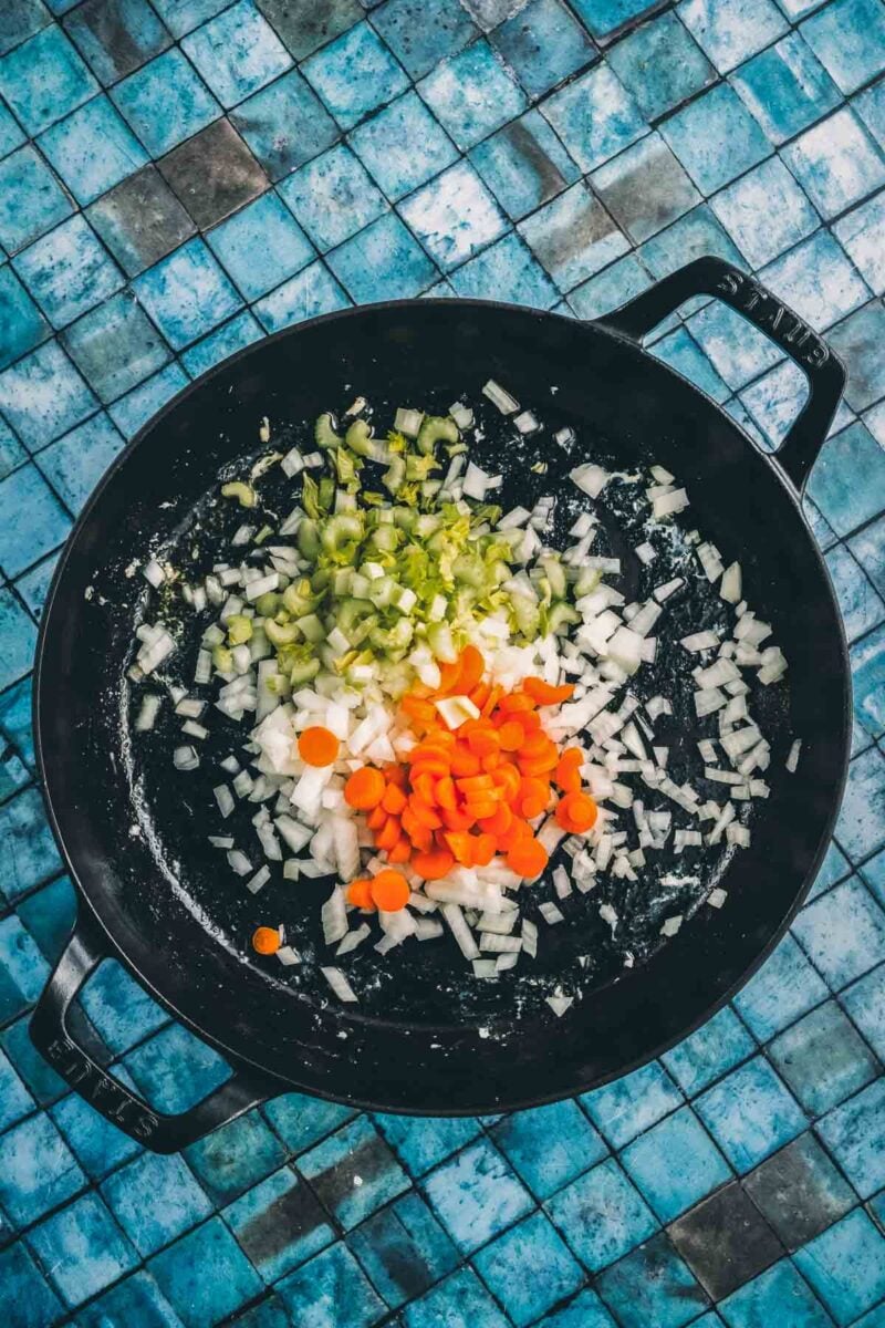 Diced onion, carrot and celery added to the same pan after the chicken comes out, still raw and ready to soften.