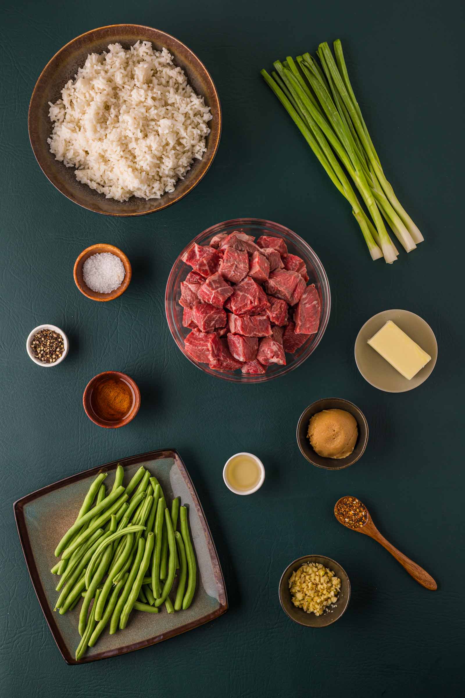 Ingredients for miso butter steak bites: cubed raw sirloin, green beans, whole scallions, white miso paste, butter, minced garlic, togarashi and white rice.