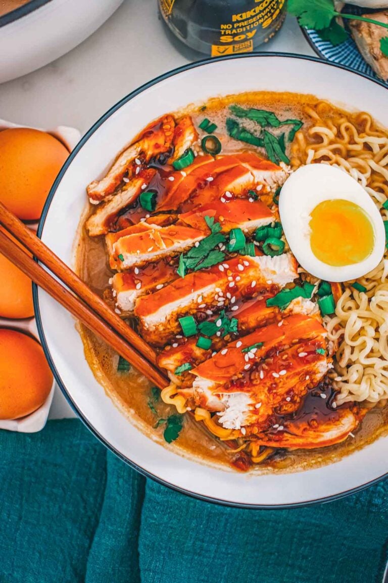Overhead bowl of teriyaki chicken ramen, sliced chicken glazed in teriyaki beside a halved jammy egg and curled ramen noodles.