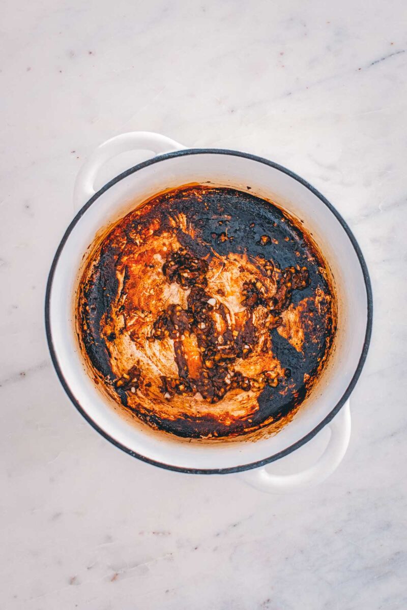 The browned teriyaki fond left in the Dutch oven after searing, with garlic and ginger added to bloom.