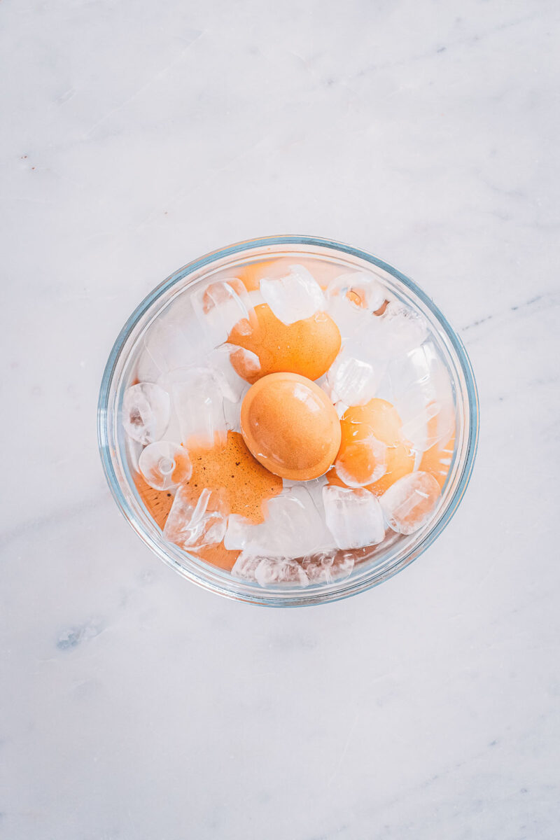 Soft-boiled eggs cooling in a bowl of ice water to stop the cooking before peeling.
