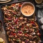 A sheet pan of Greek feta fries with the harissa yogurt sauce drizzled over the lamb, feta, tomato and red onion.