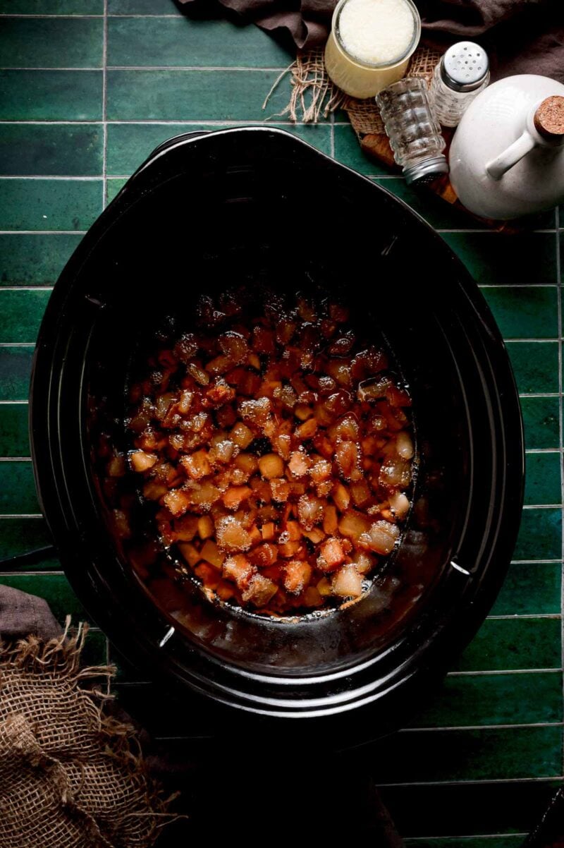 The late stage of the render, pork solids shrunken and golden with most of the liquid lard released around them in the slow cooker.