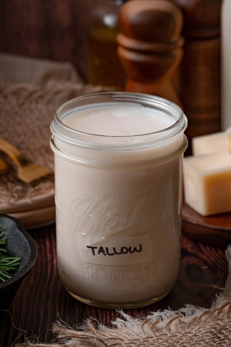 A wide mouth mason jar labeled tallow, filled to the top with beef tallow cooled to a firm, opaque cream.