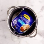 A packaged Butterball boneless turkey breast roast sits in a metal pot on a white marble surface.