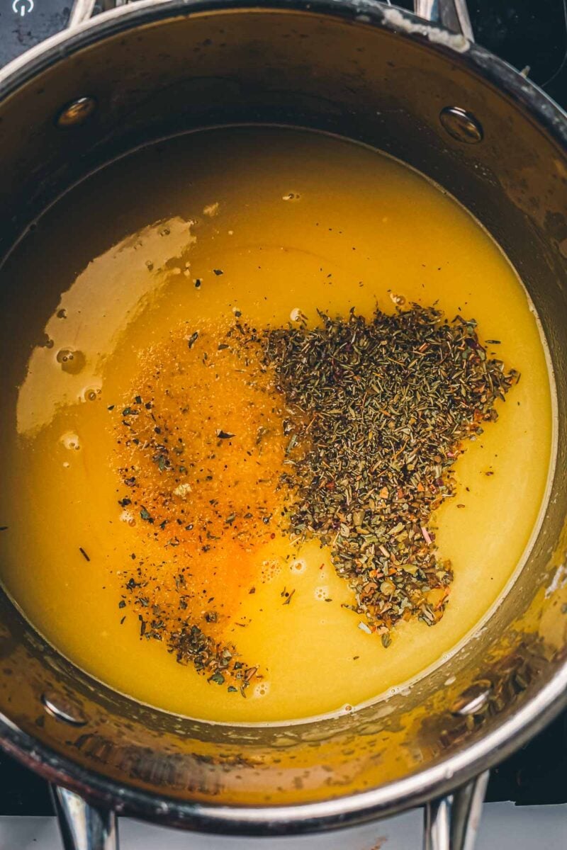 Dried herbs and seasonings scattered across the surface of the turkey gravy before they are whisked in.