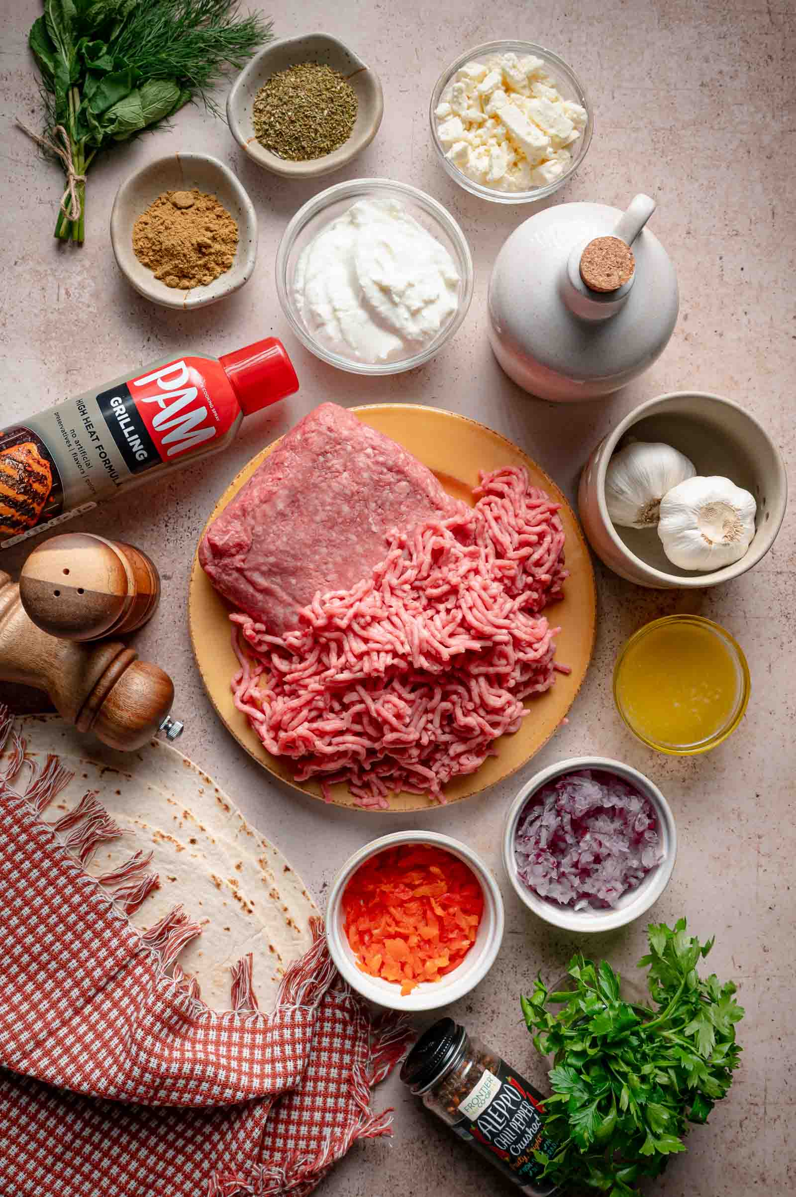 Ingredients for tortilla kebab skewers: ground lamb and beef, flour tortillas, labneh, feta, Aleppo pepper, cumin, oregano, garlic, red onion, red bell pepper, dill, mint and parsley.