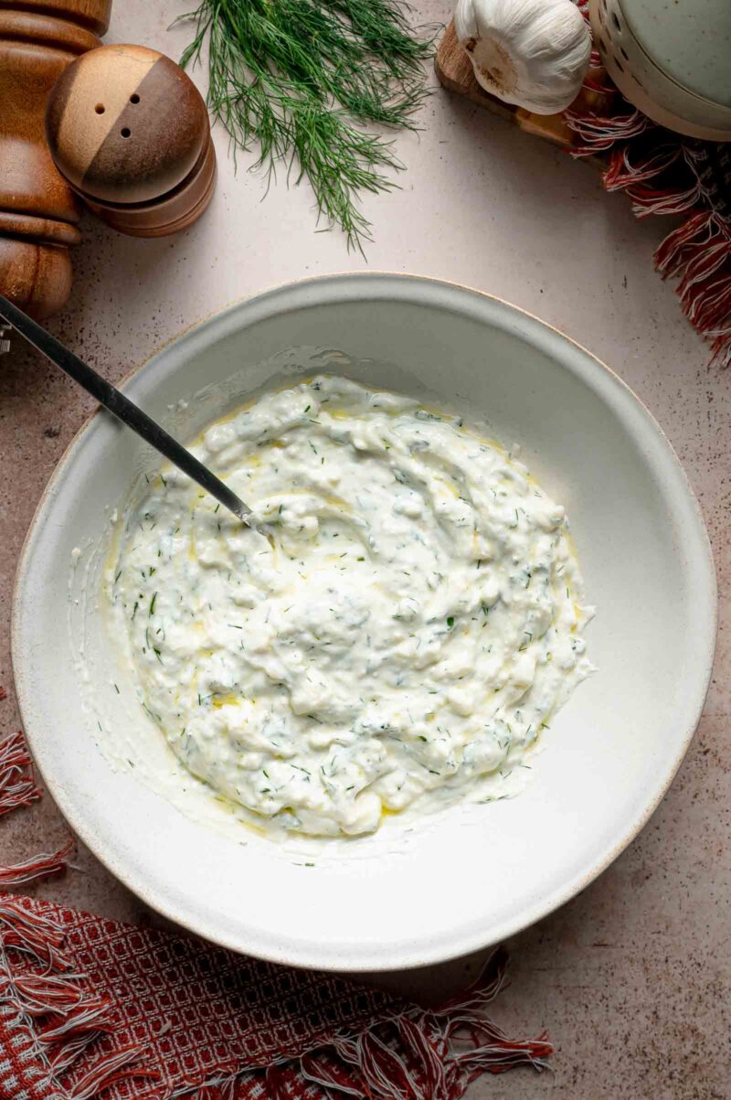 The finished haydari, thick labneh and feta stirred smooth with dill and mint and drizzled with olive oil.