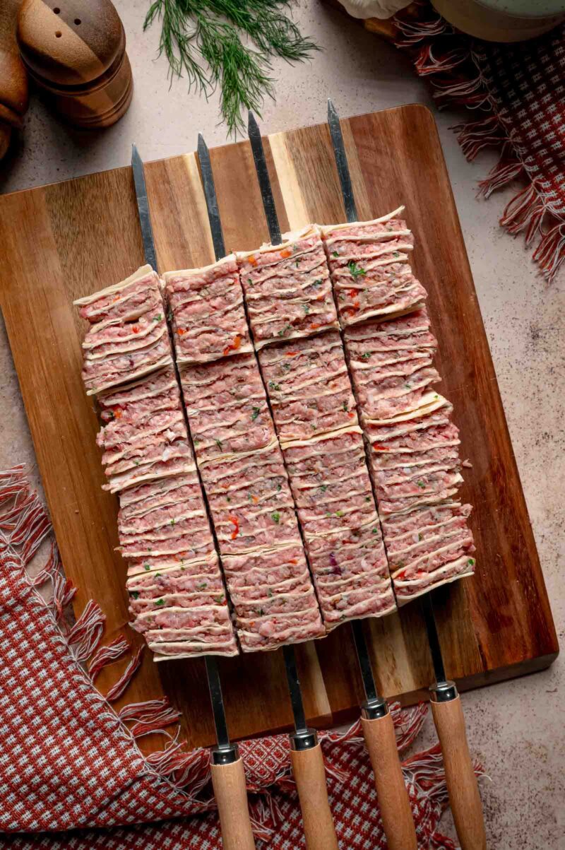 The skewers pushed through and the stack cut between them, leaving four loaded tortilla kebab skewers ready to grill.