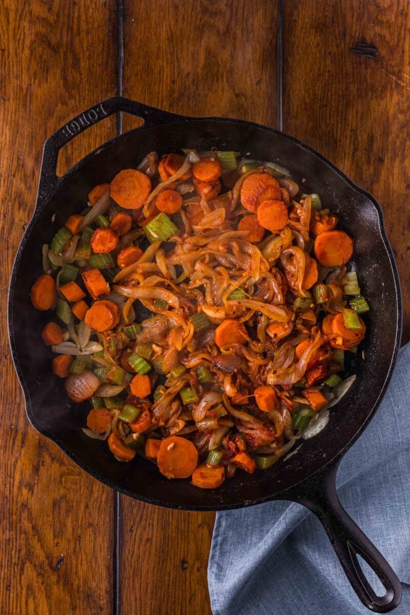 The tomato paste cooked into the vegetables until it darkens to deep rust, the step that builds the gravy's backbone.